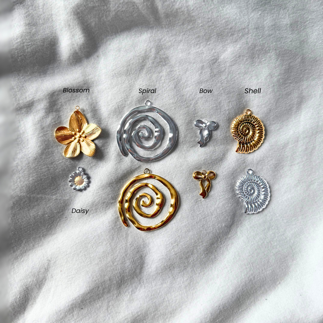Collection of gold and silver jewelry charms on a textured white surface