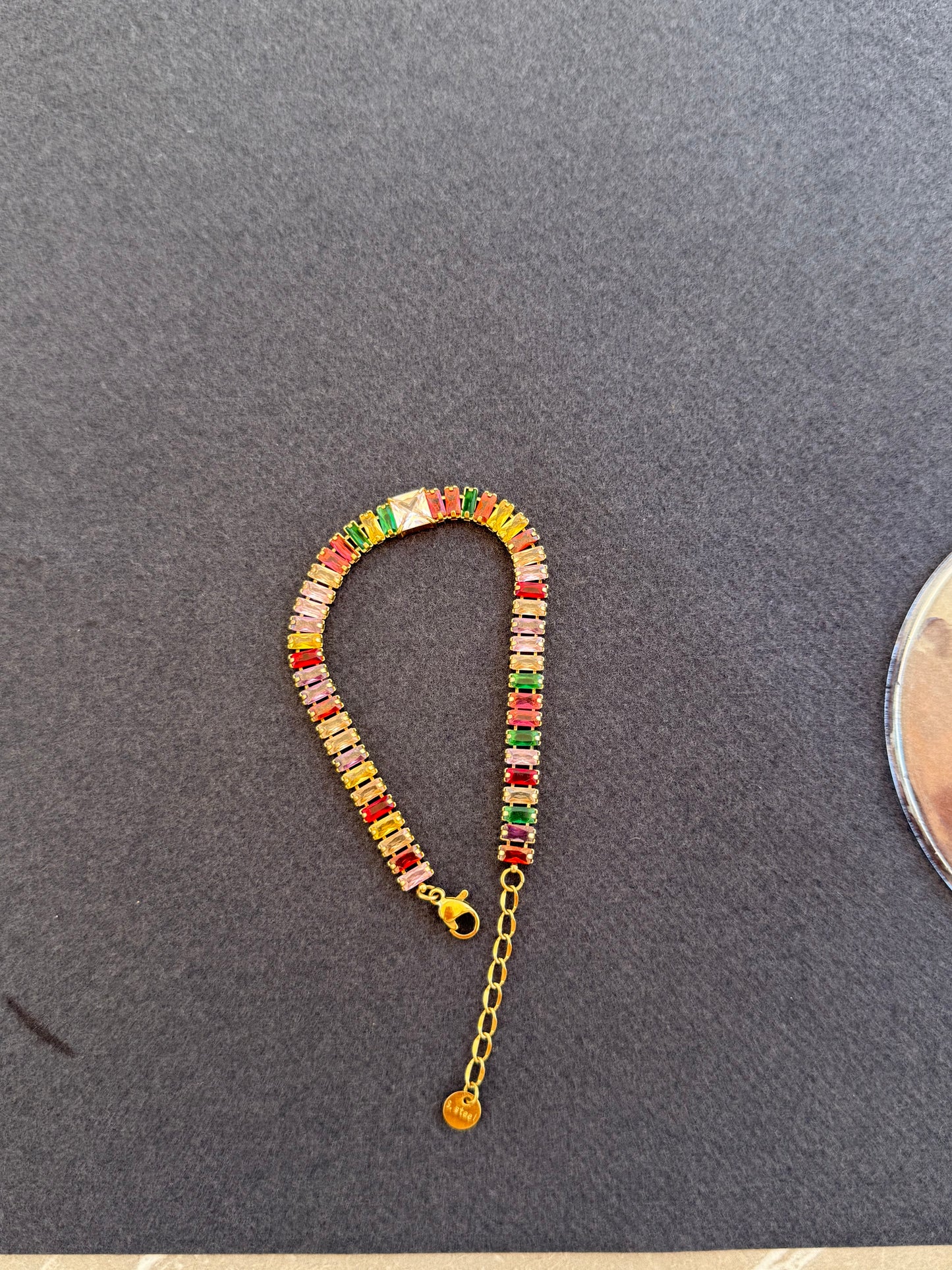 Colorful beaded bracelet with a gold chain on a gray surface