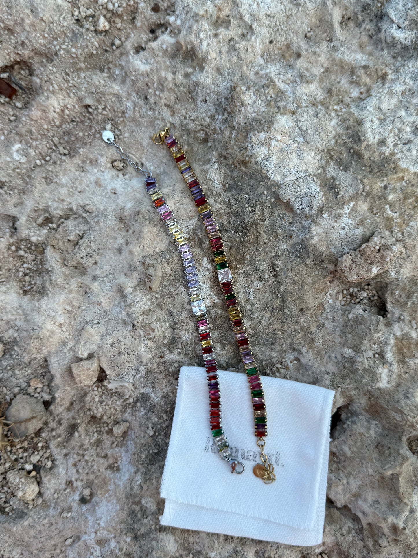 Colorful beaded BRACELET on a white cloth with a textured stone background