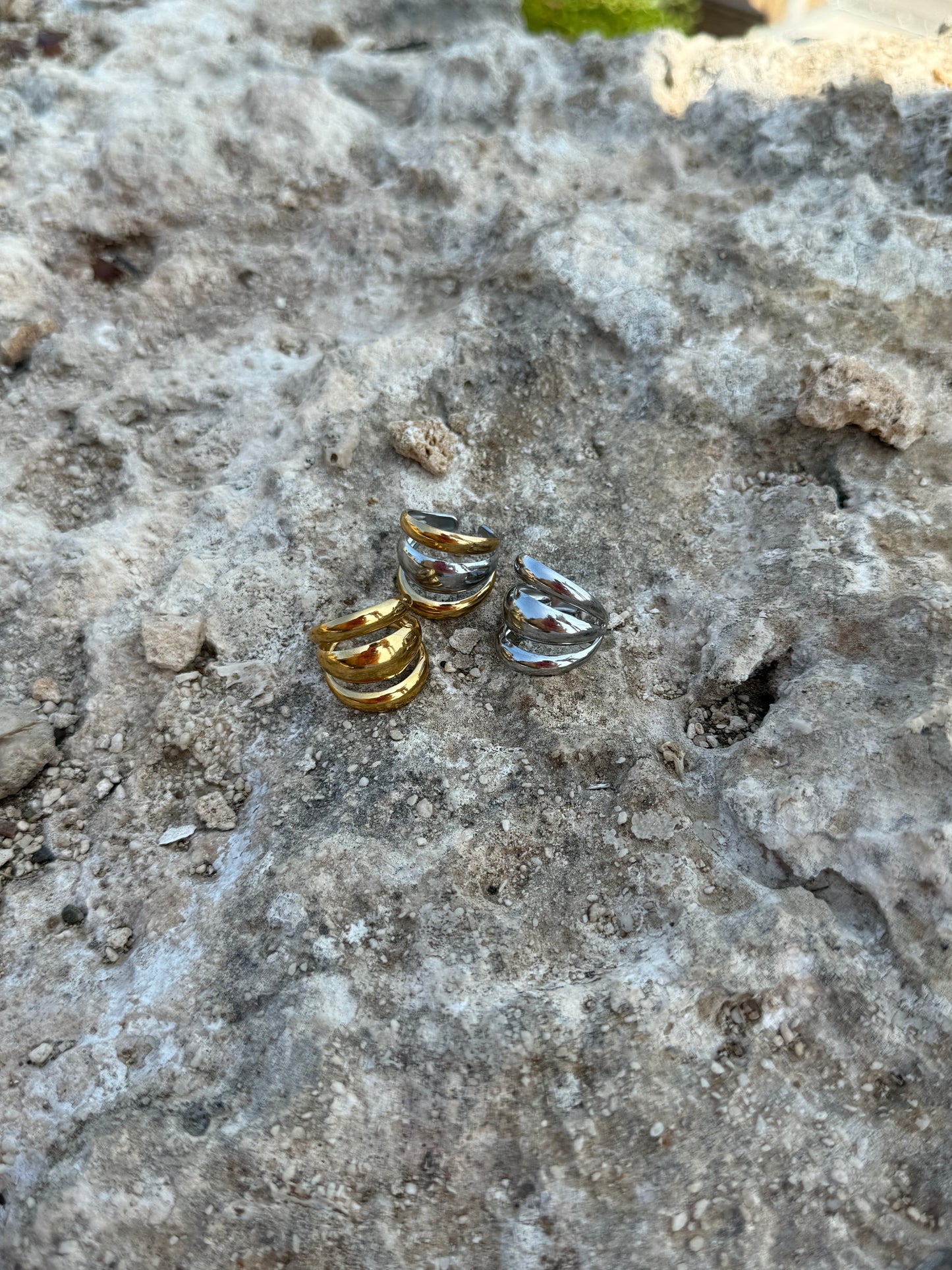 Three small gold and silver rings on a textured stone surface