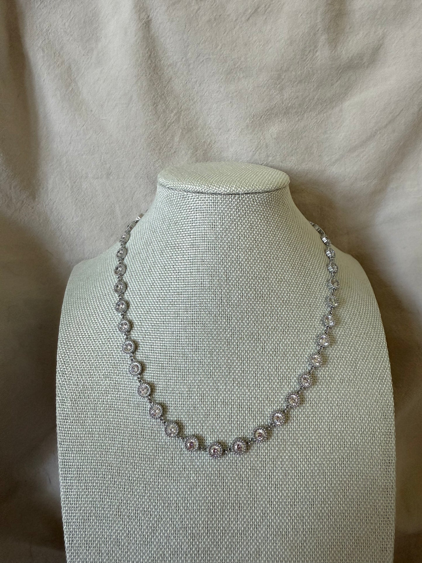 Pearl necklace on a mannequin bust against a beige fabric background