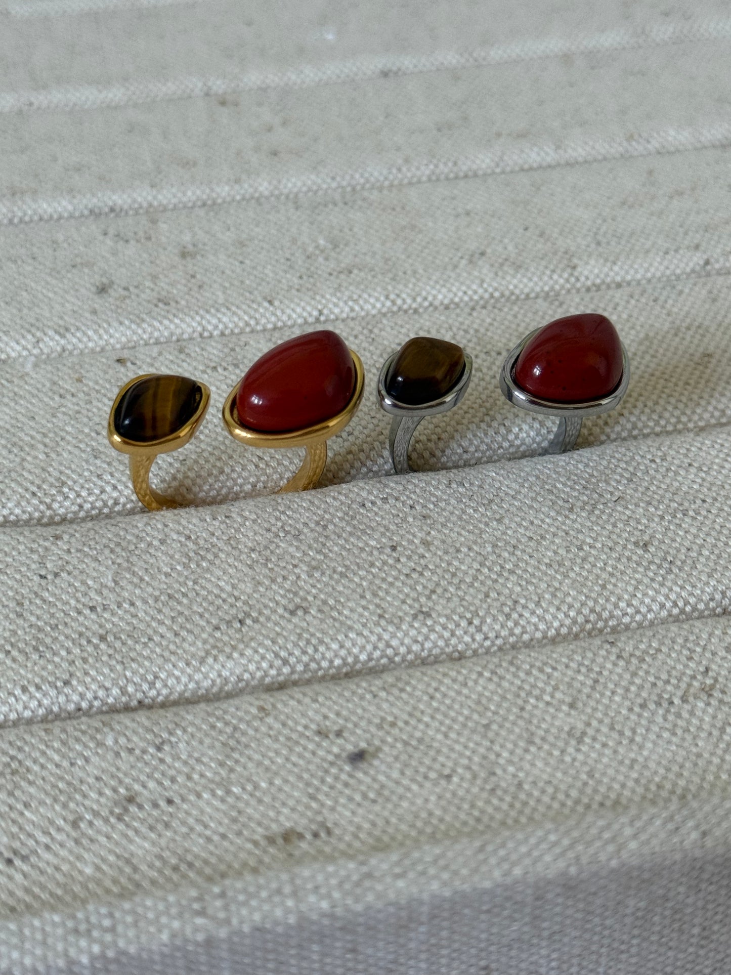 TWO rings with different RED colored stones on a textured fabric background