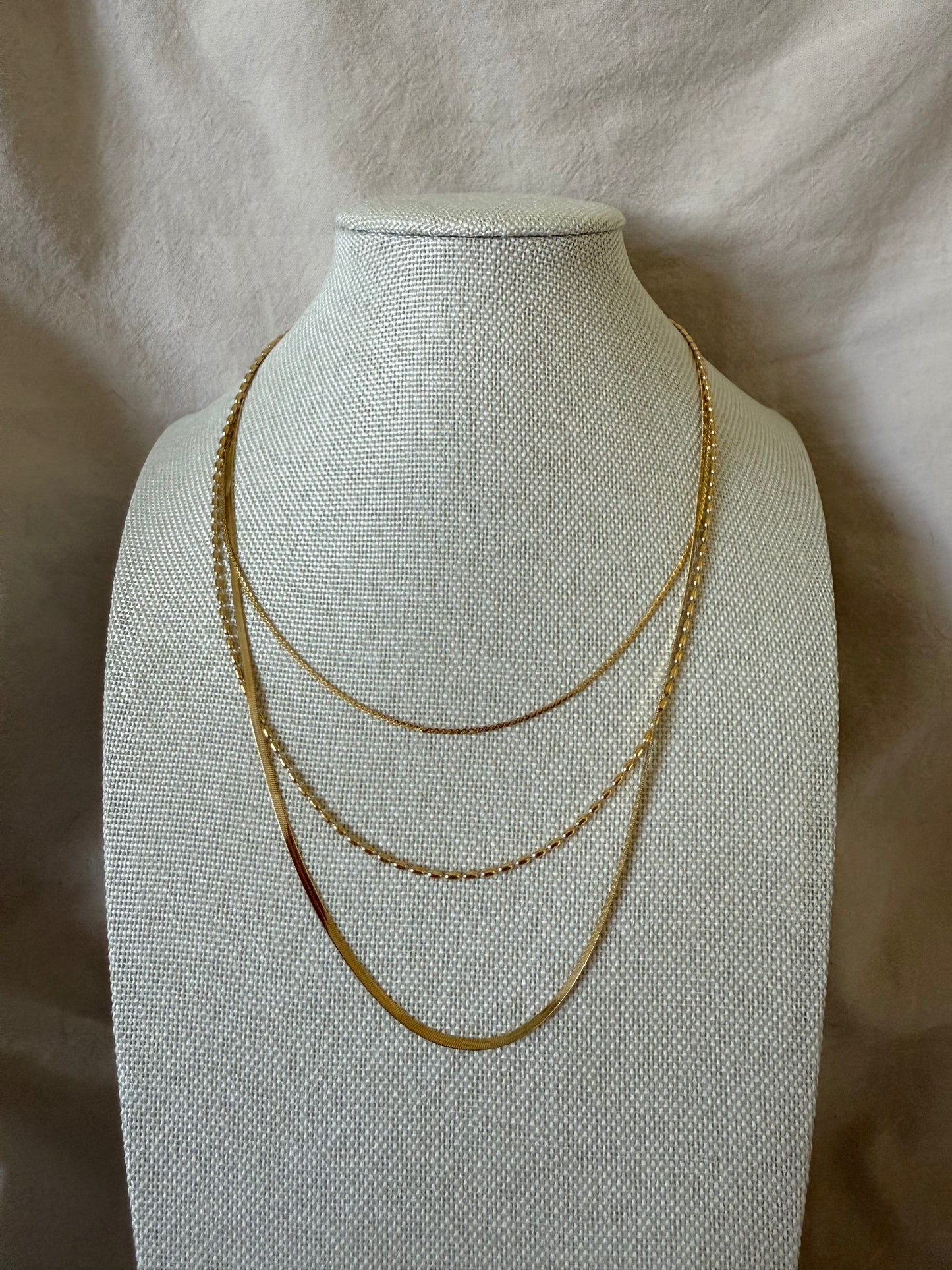 Gold necklace on a mannequin bust against a beige background