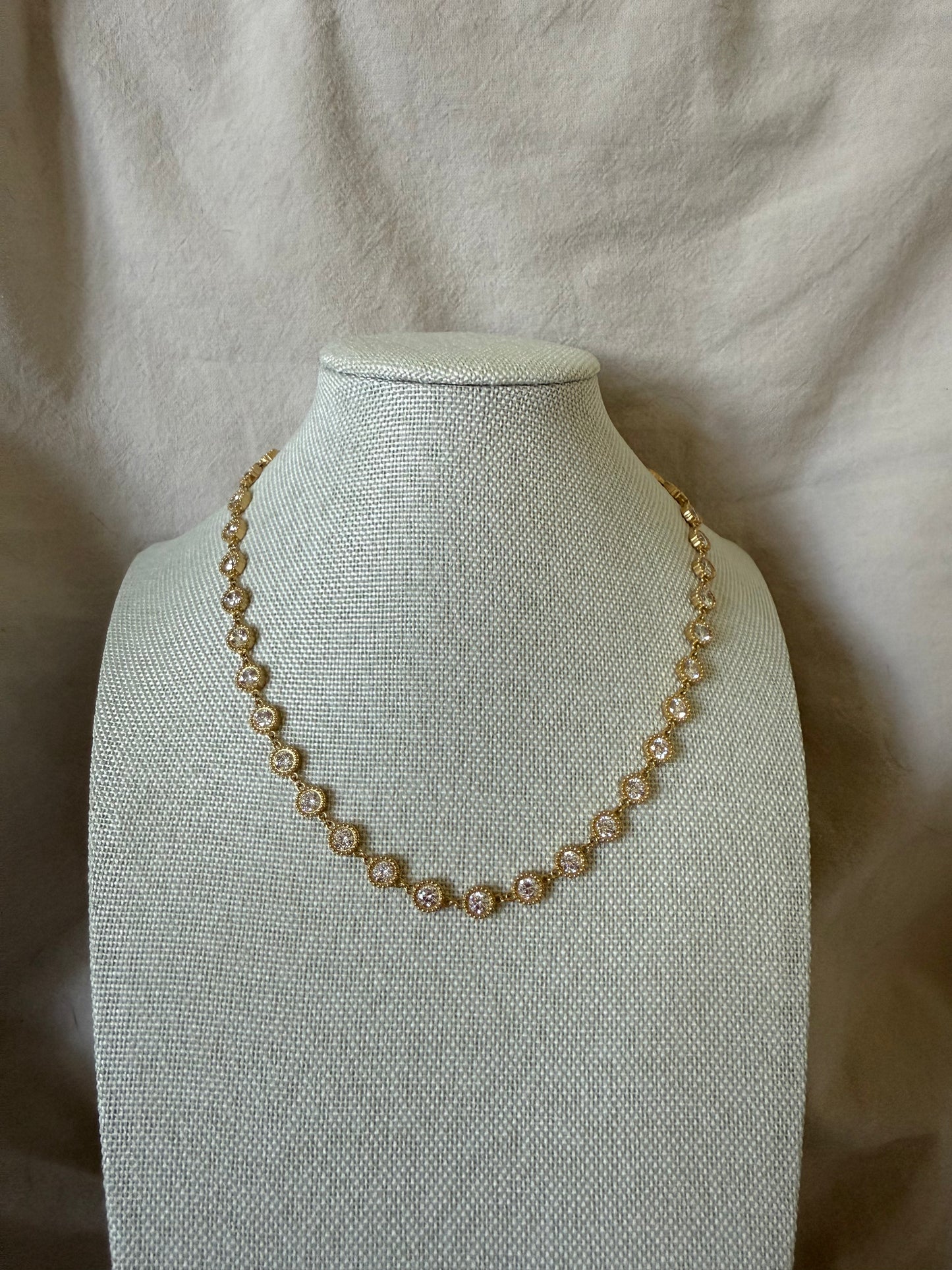 Pearl necklace on a mannequin bust against a beige fabric background