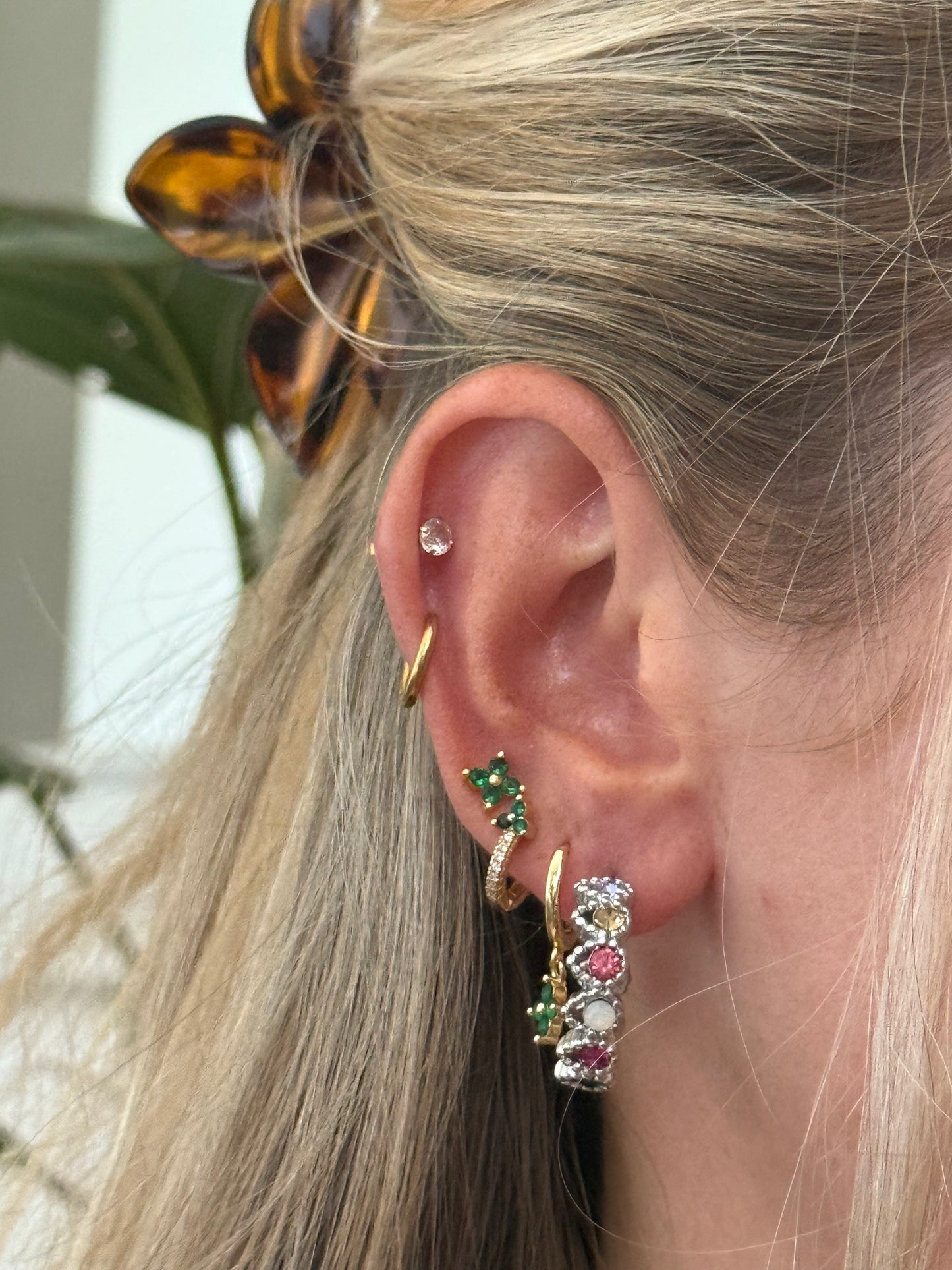 Close-up of an ear with multiple earrings and a hair clip.