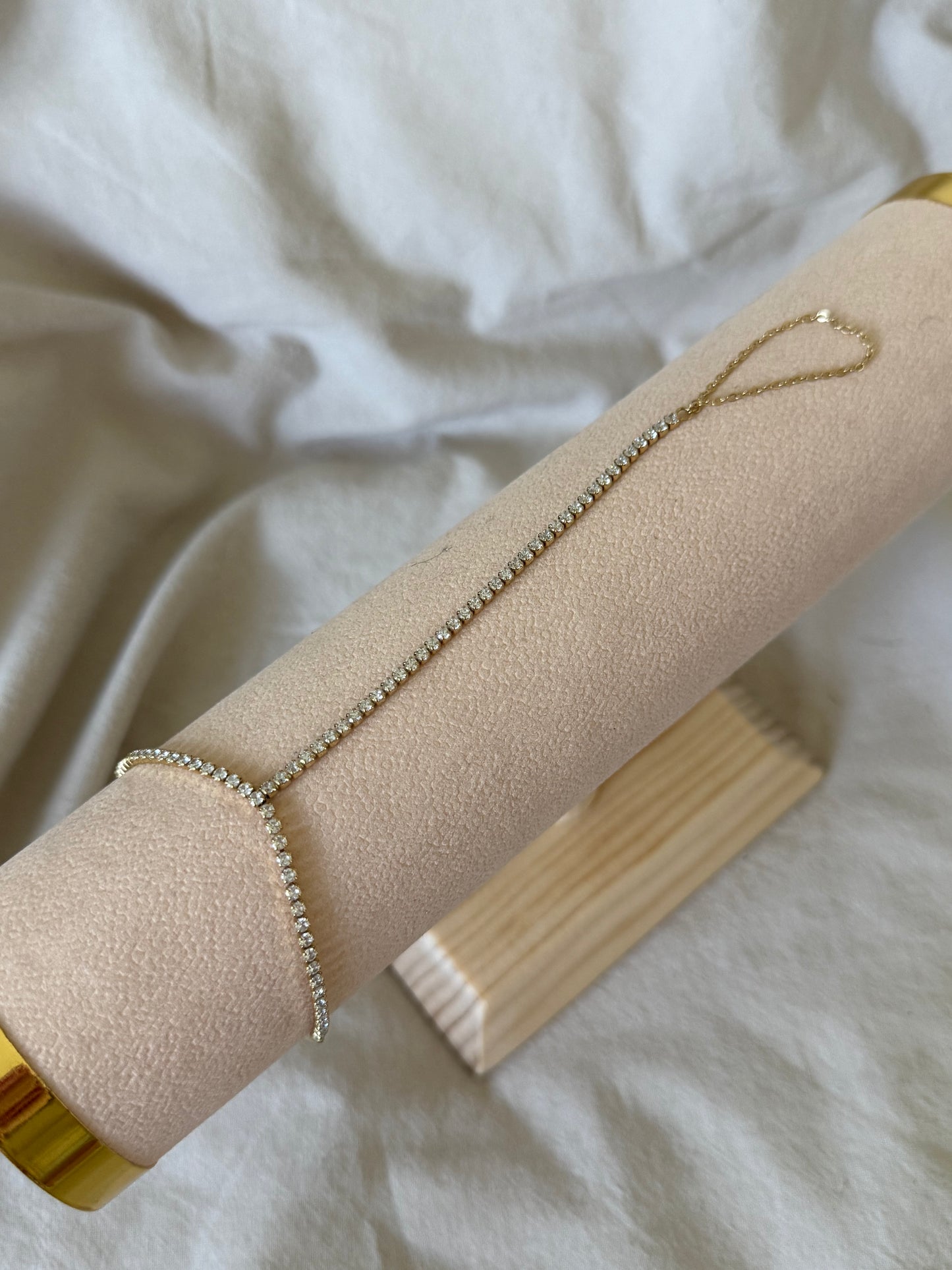 Delicate TENNIS HAND CHAIN on a beige jewelry roll with a white fabric background