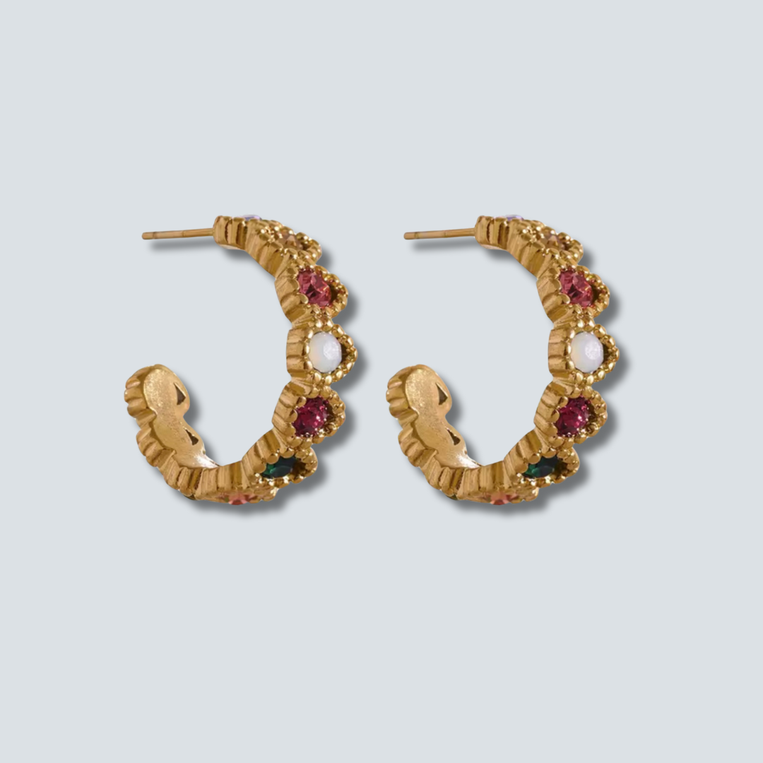 Gold hoop earrings with gemstones on a light gray background