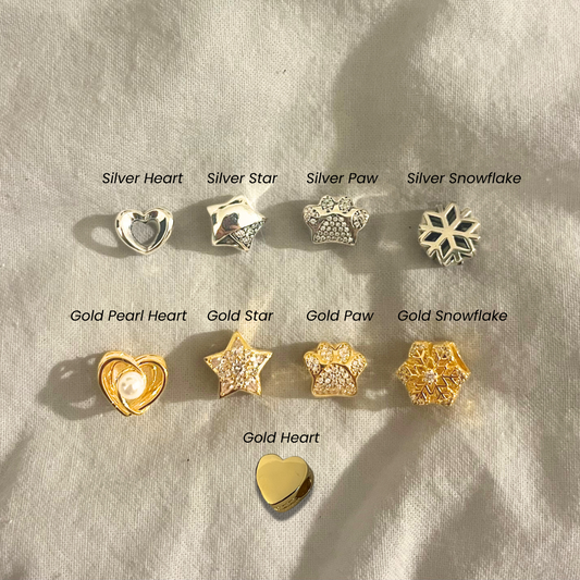 Collection of gold and silver jewelry charms on a textured surface