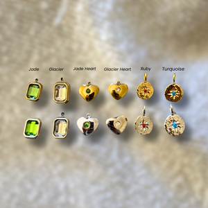 Collection of gold pendants with gemstones on a textured beige background