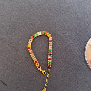 Colorful beaded bracelet with a gold chain on a gray surface