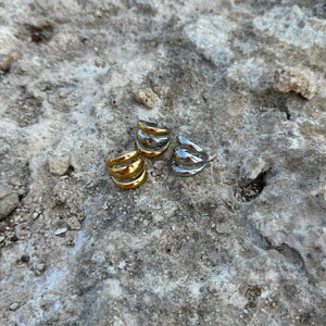 Three small gold and silver rings on a textured stone surface