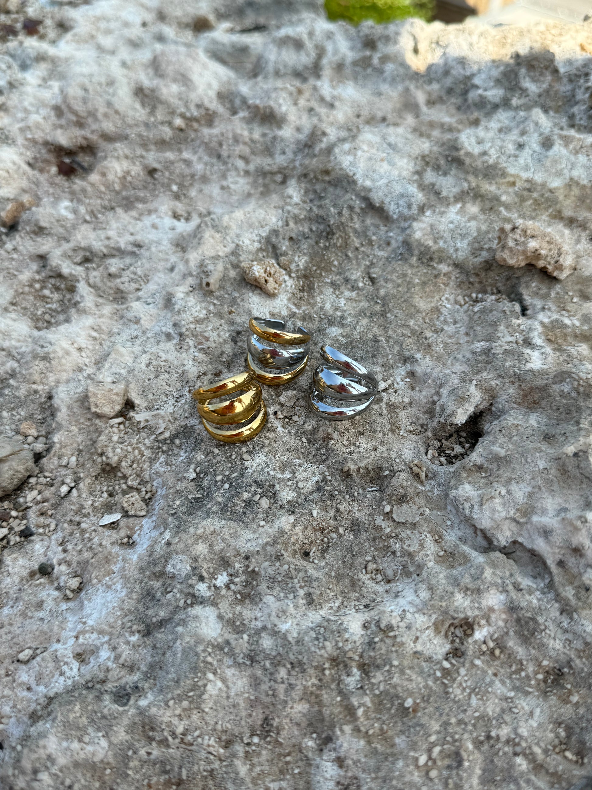 Three small gold and silver rings on a textured stone surface