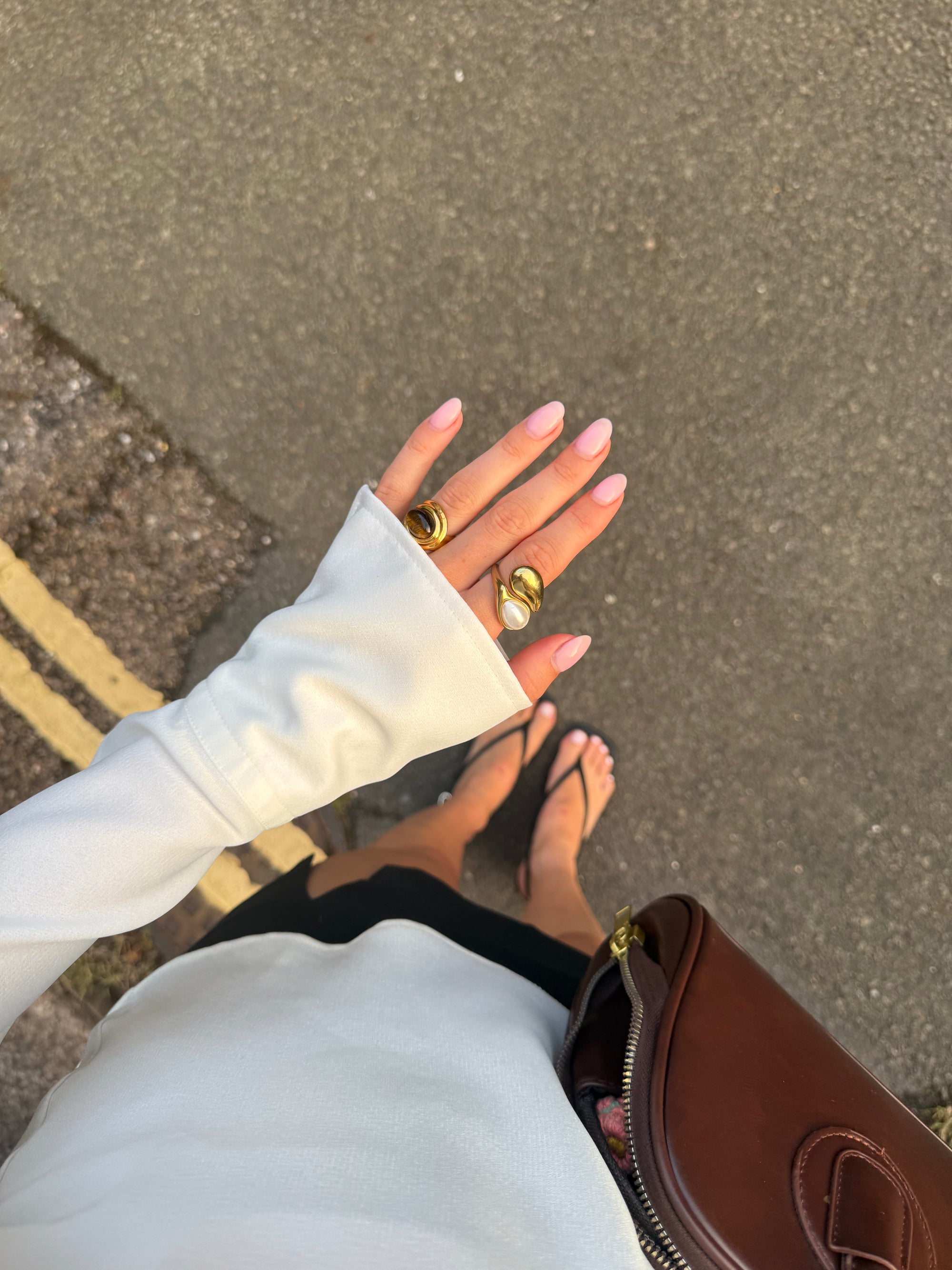 Close-up of a person's hands with white gloves and gold rings on a concrete surface.