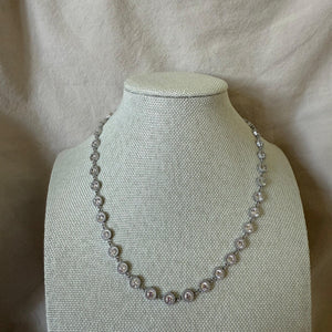 Pearl necklace on a mannequin bust against a beige fabric background
