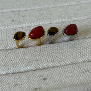 TWO rings with different RED colored stones on a textured fabric background