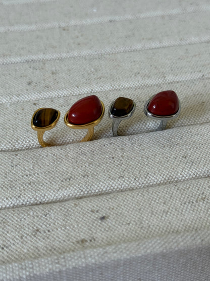 TWO rings with different RED colored stones on a textured fabric background