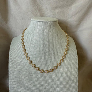 Pearl necklace on a mannequin bust against a beige fabric background