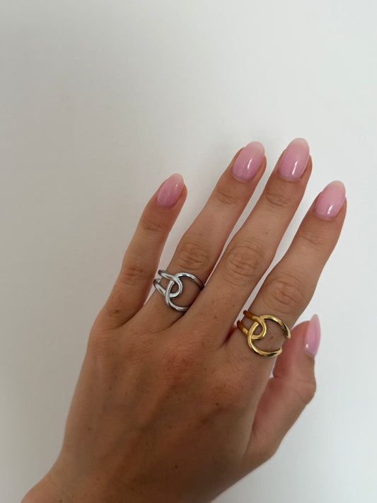 Hand wearing two rings with a plain background