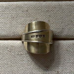 Gold spoon ring on a textured beige surface