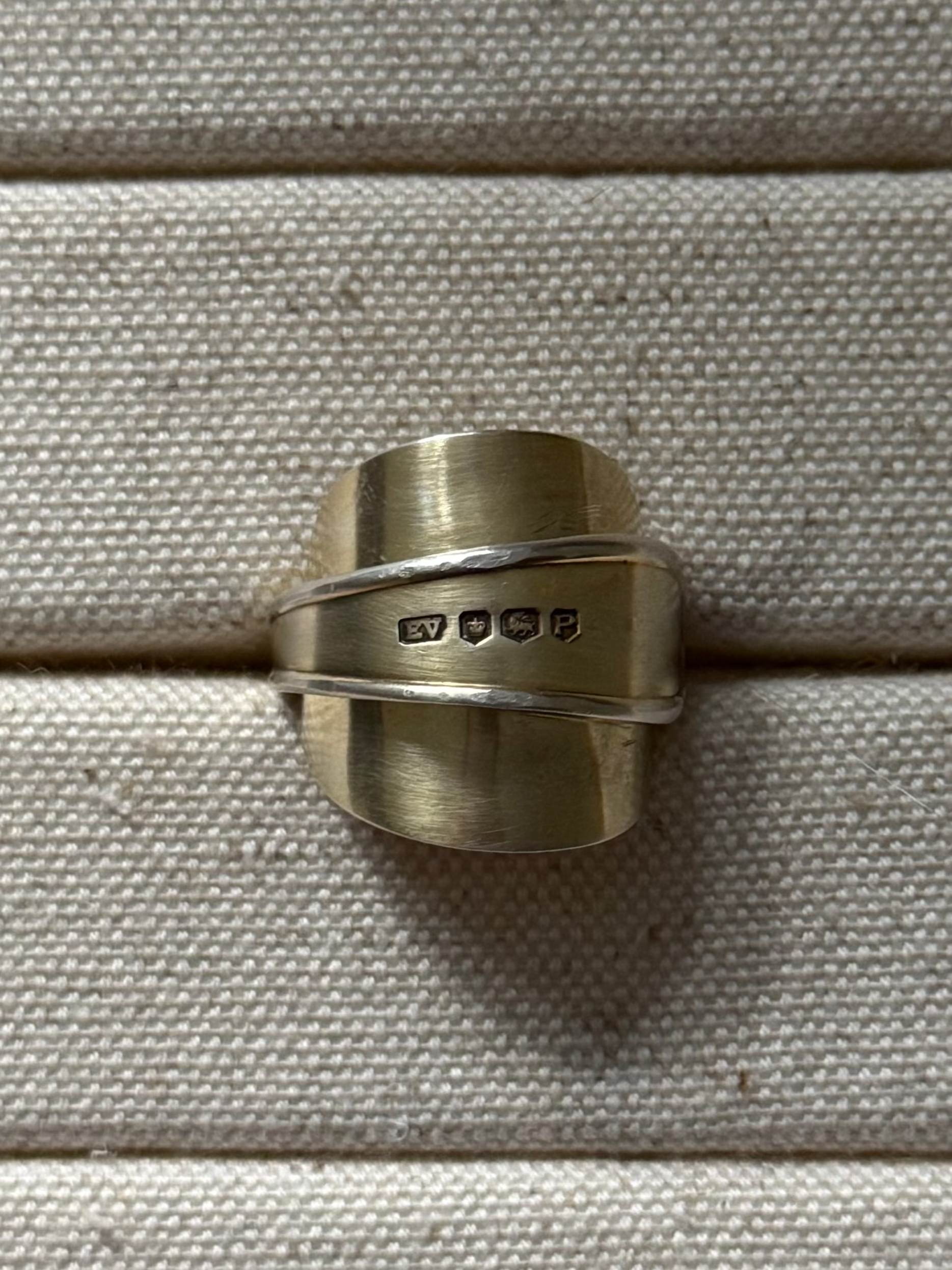 Gold spoon ring on a textured beige surface