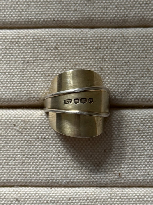 Gold spoon ring on a textured beige surface
