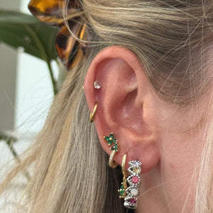 Close-up of an ear with multiple earrings and a hair clip.