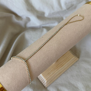 Delicate TENNIS HAND CHAIN on a beige jewelry roll with a white fabric background