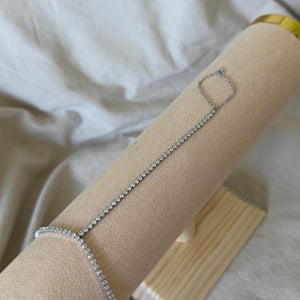 Silver bracelet/HAND CHAIN  on a beige cylindrical display with a white fabric background