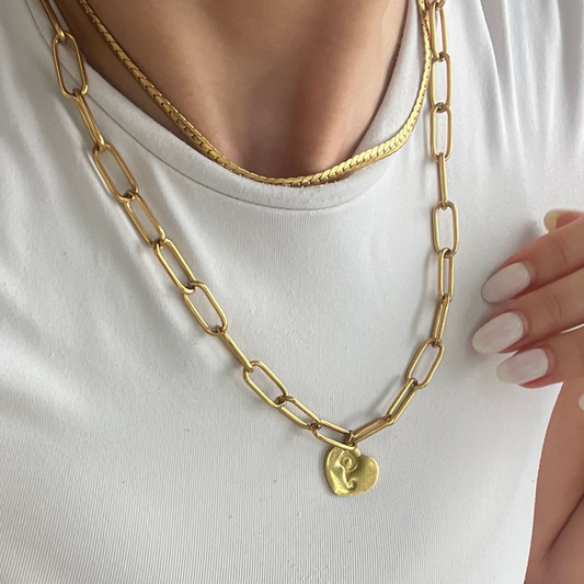 Person wearing a white top and blue shorts with gold jewelry outdoors
