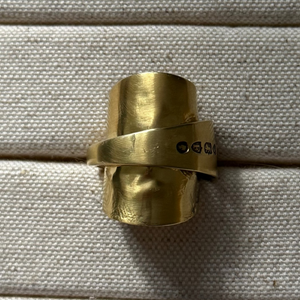 Gold SPOON ring on a textured beige surface