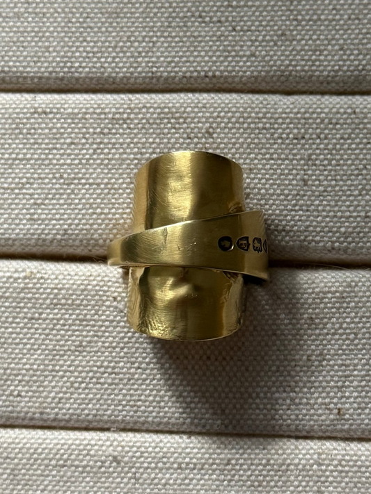 Gold SPOON ring on a textured beige surface