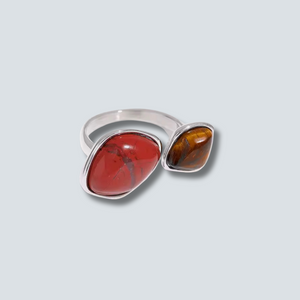 Silver ring with red and brown stones on a light gray background