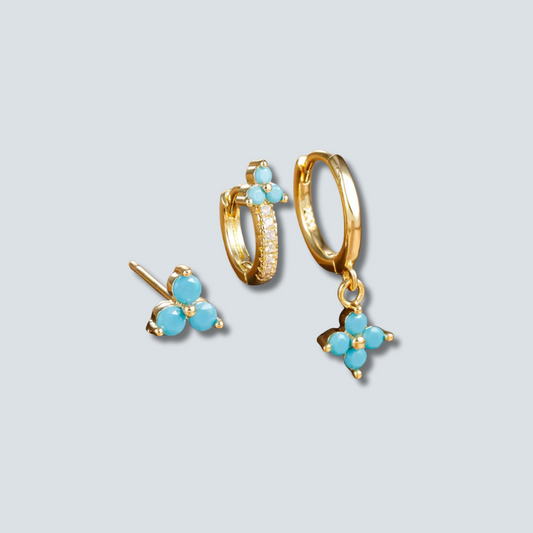 Set of gold hoop earrings with turquoise stones on a light gray background