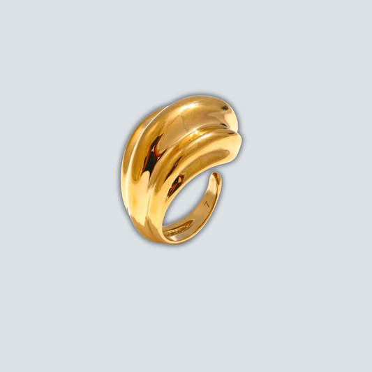 Gold ring with a wavy design on a light gray background