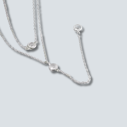 Silver necklace with small round pendants on a light gray background