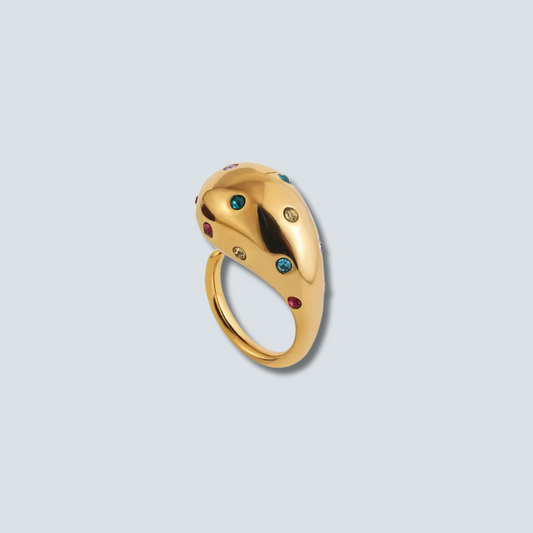 Gold ring with colored gemstones on a light gray background