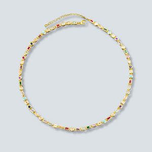 Gold necklace with colorful gemstones on a light gray background