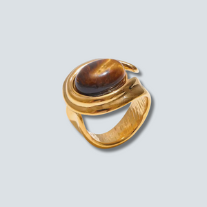Gold ring with a brown gemstone on a light gray background