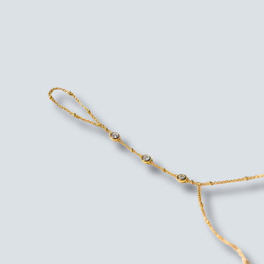 Gold HAND CHAIN with small stones on a light gray background