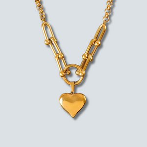 Gold chain necklace with a heart pendant on a light gray background