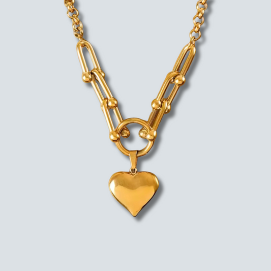 Gold chain necklace with a heart pendant on a light gray background