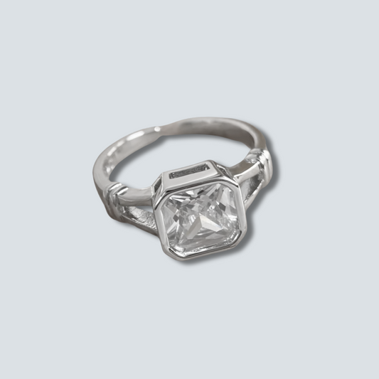 Silver ring with a large diamond on a light gray background