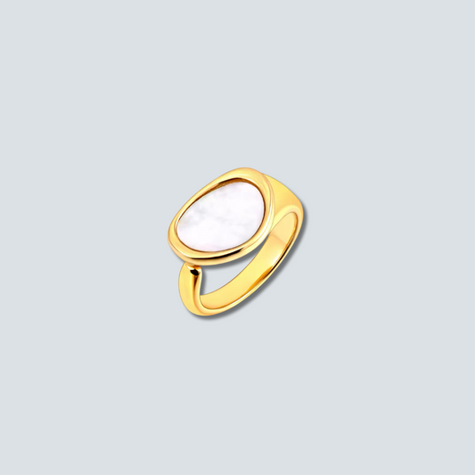 Gold ring with a white stone on a light gray background