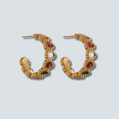 Gold hoop earrings with gemstones on a light gray background