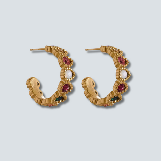 Gold hoop earrings with gemstones on a light gray background
