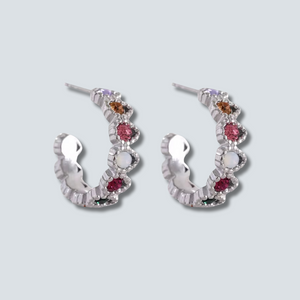Pair of silver hoop earrings with gemstones on a light gray background