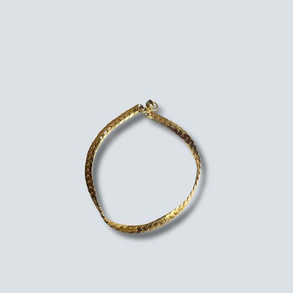 Gold bracelet on a light gray background