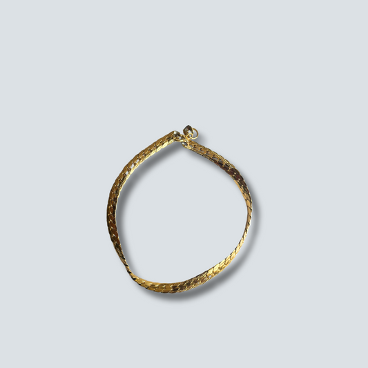 Gold bracelet on a light gray background