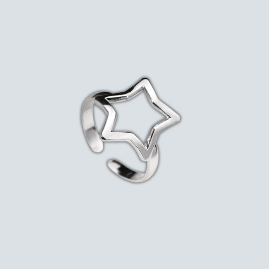 Silver star-shaped ring on a light gray background