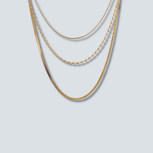 Three gold necklaces of different thicknesses on a light gray background